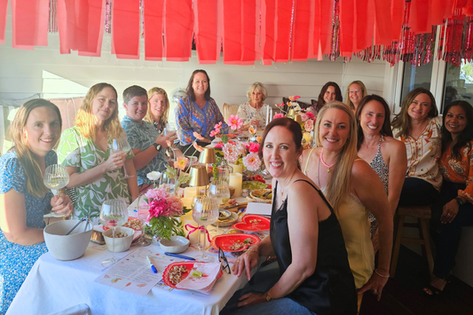 Women smiling sitting around a table with gin glasses.